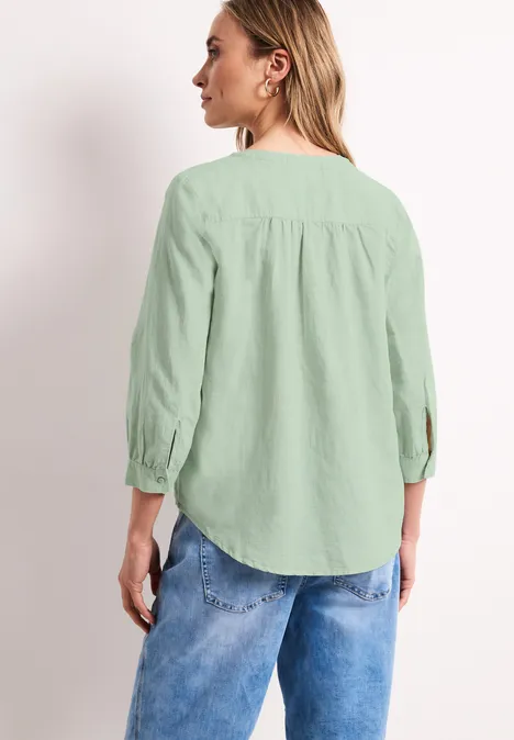 Frau von hinten in hellgrüner Bluse und Jeans, 3/4-Ärmel, geraffter Rücken